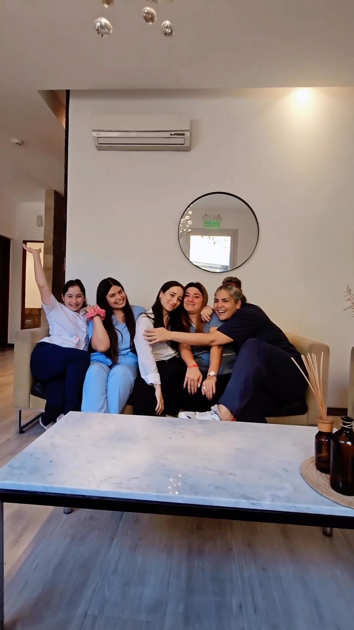 Cinco integrantes del equipo de Prometeo, sonrientes y abrazadas en el sillón de la recepción, frente a una mesa de mármol